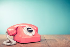 Retro roze telefoon op een houten tafel met een blauwe achtergrond