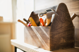 Een houten gereedschapskist met verschillende stukken gereedschap erin staat op een houten tafel.